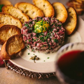 A plate of steak tartare with wine and an egg yolk.