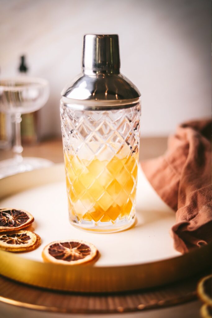 Adding the ingredients to a cocktail shaker filled with ice. 