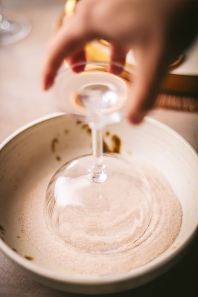 Rimming the cocktail glass with sugar and cinnamon, plus lemon juice to make it stick. 