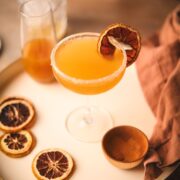 An apple sidecar cocktail with dehydrated orange and sugar/cinnamon rim.