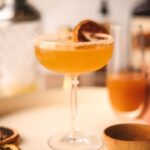 An apple sidecar with napkin, serving tray and ingredients in the background.